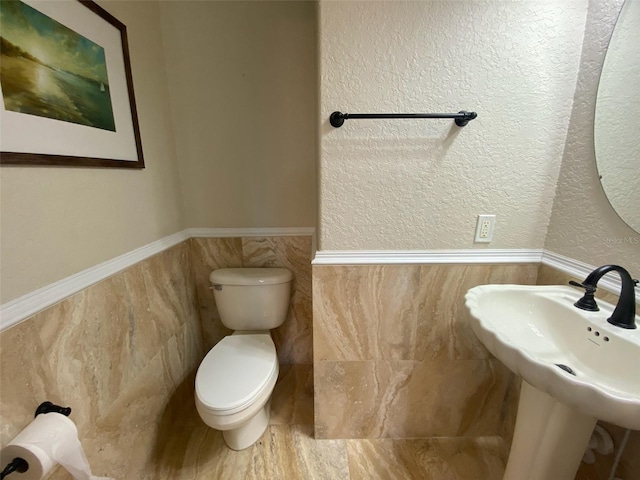 bathroom featuring sink, tile walls, and toilet