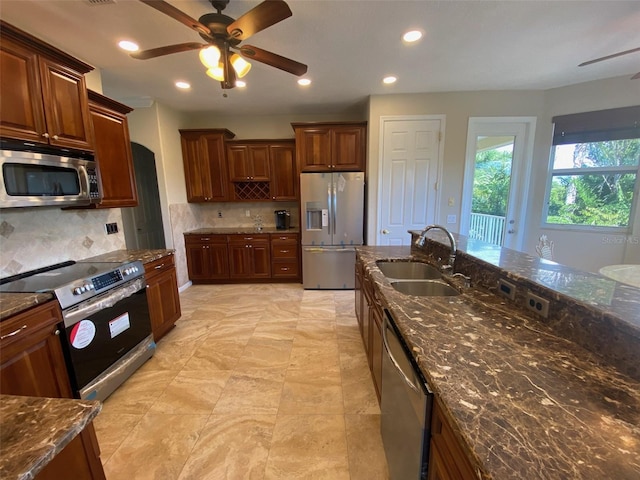 kitchen featuring sink, stainless steel appliances, dark stone counters, and tasteful backsplash