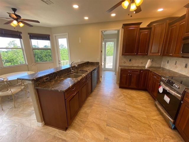 kitchen with dark stone counters, a kitchen breakfast bar, sink, decorative backsplash, and range with electric stovetop