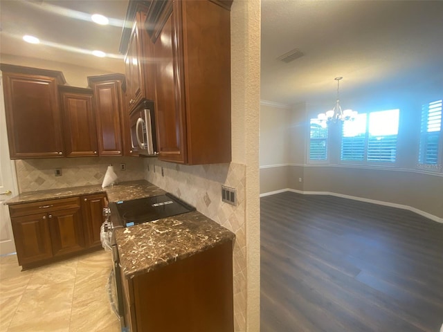 kitchen with decorative backsplash, appliances with stainless steel finishes, ornamental molding, light hardwood / wood-style flooring, and a chandelier