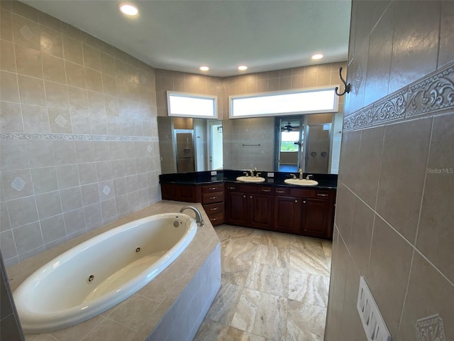 bathroom featuring separate shower and tub, vanity, and tile walls