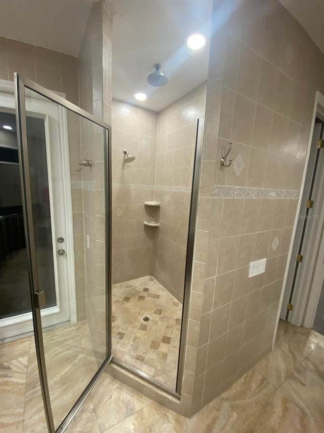 bathroom with an enclosed shower and tile walls