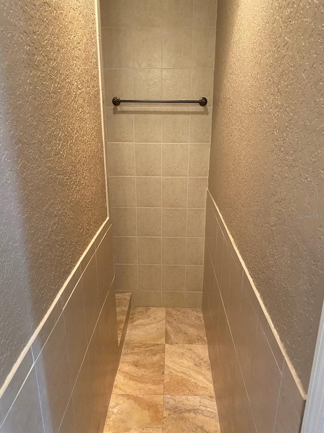 bathroom featuring a tile shower and tile walls