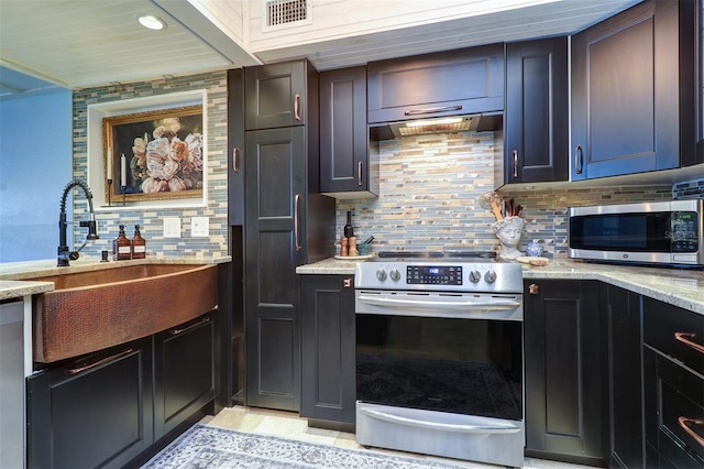 kitchen with appliances with stainless steel finishes, tasteful backsplash, light stone counters, and sink