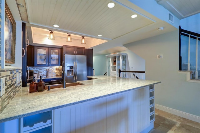 kitchen featuring kitchen peninsula, tasteful backsplash, track lighting, sink, and stainless steel fridge with ice dispenser