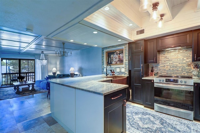 kitchen with tasteful backsplash, light stone counters, stainless steel range with electric stovetop, decorative light fixtures, and a kitchen island with sink