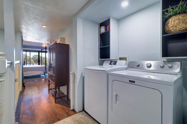 washroom with a textured ceiling, dark hardwood / wood-style floors, and washing machine and clothes dryer