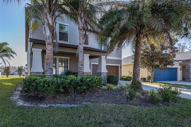 view of front facade featuring a front yard, concrete driveway, and stucco siding