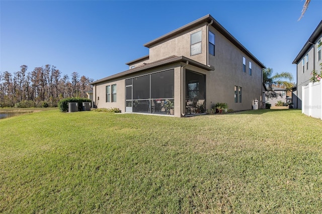 back of house featuring a sunroom, a lawn, and stucco siding