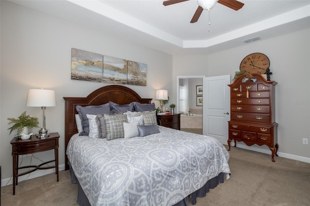 carpeted bedroom with ensuite bathroom, a ceiling fan, visible vents, baseboards, and a raised ceiling