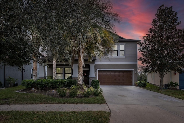 view of front facade with a garage, concrete driveway, and stucco siding