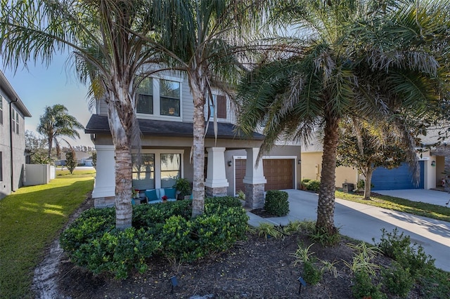 view of front of house with a front yard, concrete driveway, and stucco siding