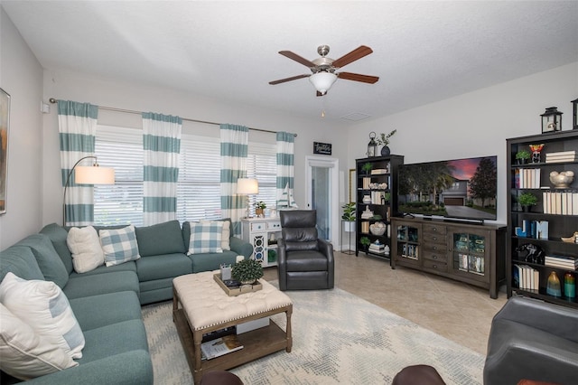 living room featuring tile patterned flooring, visible vents, ceiling fan, and a textured ceiling