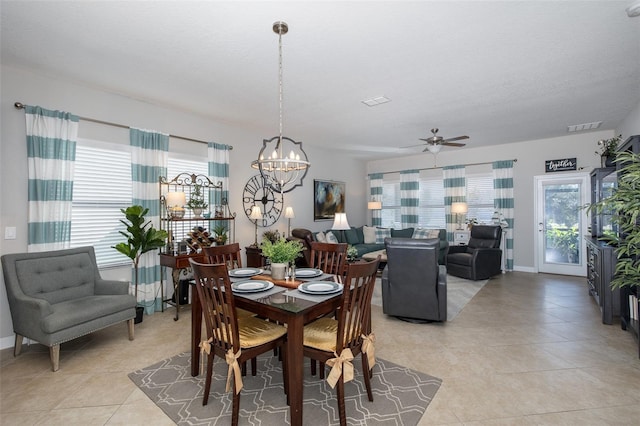 tiled dining room with ceiling fan with notable chandelier and a wealth of natural light