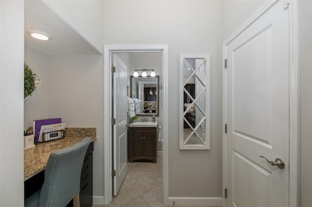 interior space featuring light tile patterned flooring, a sink, and baseboards