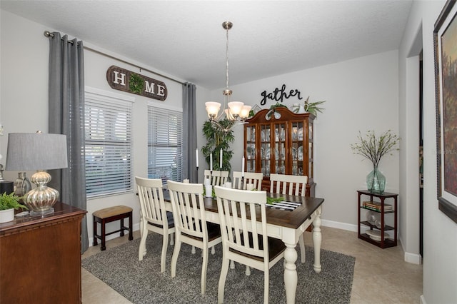 dining area with a textured ceiling, baseboards, and an inviting chandelier