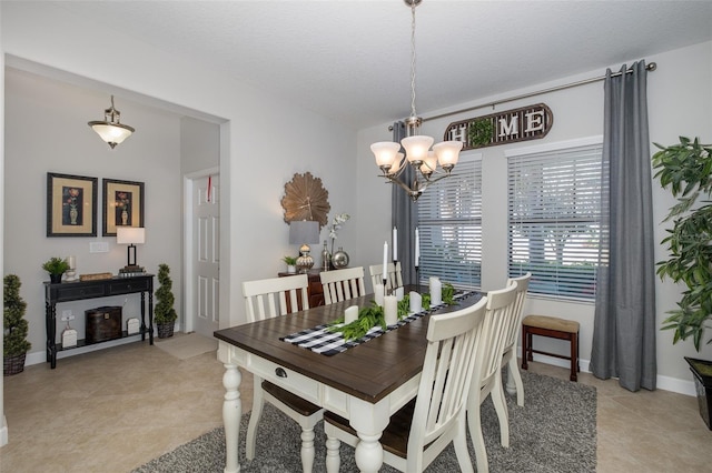 dining area featuring a chandelier, a textured ceiling, and baseboards