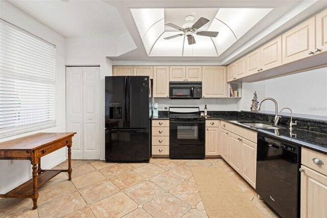 kitchen with black appliances, sink, ceiling fan, dark stone countertops, and cream cabinetry