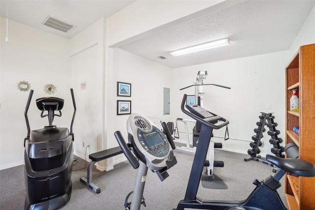 workout area with a textured ceiling and electric panel