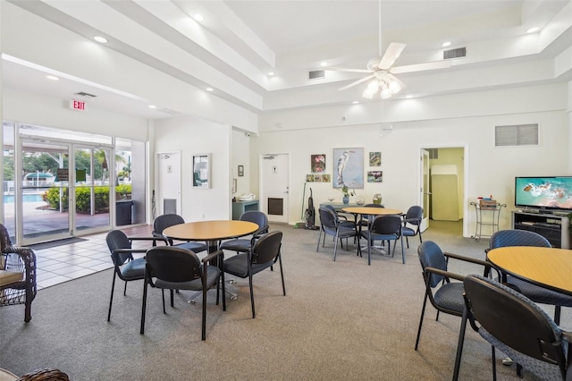 dining room featuring light carpet, a raised ceiling, and ceiling fan