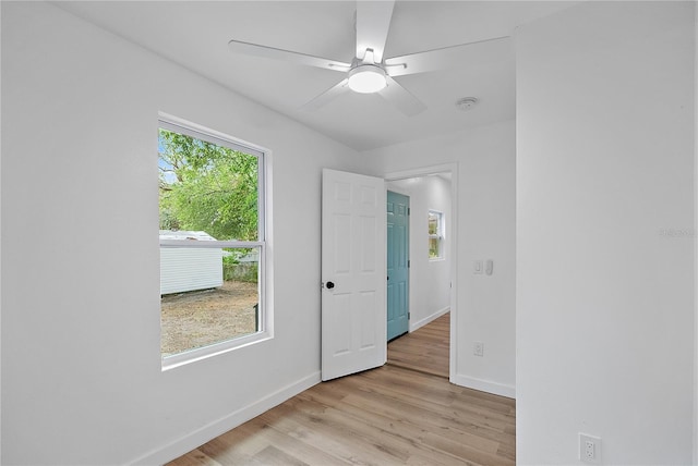 empty room with ceiling fan, plenty of natural light, and light hardwood / wood-style floors