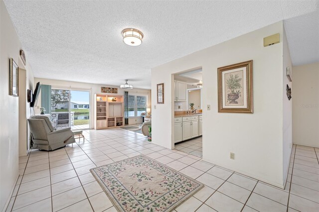 living room with a textured ceiling, ceiling fan, and light tile patterned flooring