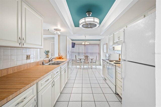 kitchen with sink, white cabinets, decorative light fixtures, and white appliances