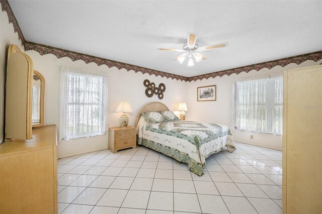 bedroom with a textured ceiling, ceiling fan, and light tile patterned flooring