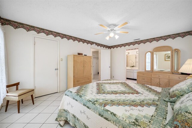 bedroom with ceiling fan, light tile patterned floors, ensuite bathroom, and a textured ceiling