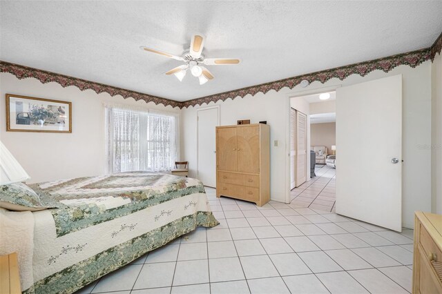 tiled bedroom with ceiling fan and a textured ceiling