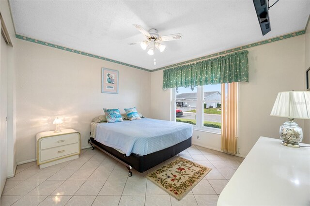 tiled bedroom with ceiling fan and a textured ceiling