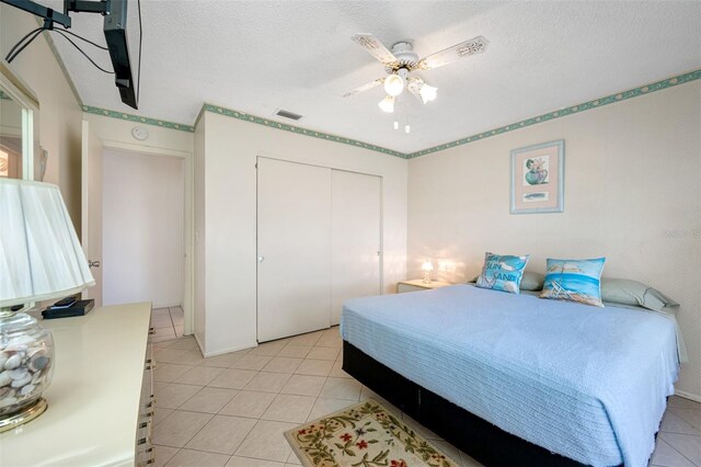 tiled bedroom featuring ceiling fan, a closet, and a textured ceiling