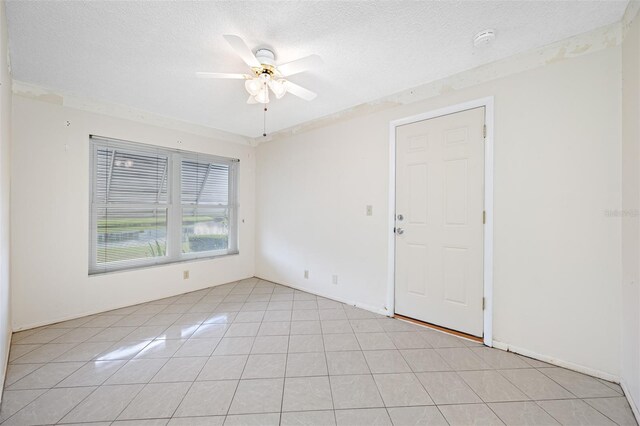 tiled empty room featuring ceiling fan and a textured ceiling