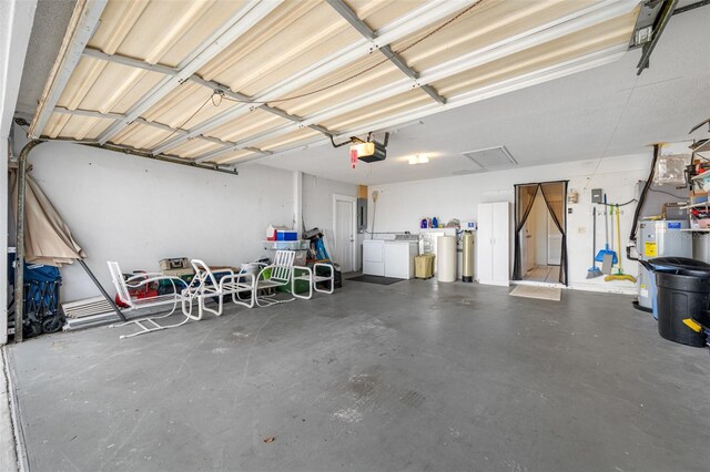 garage featuring gas water heater, independent washer and dryer, and a garage door opener