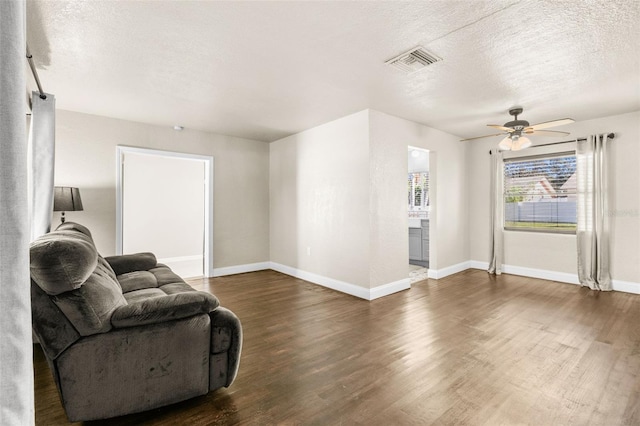 living room with ceiling fan, dark hardwood / wood-style flooring, and a textured ceiling