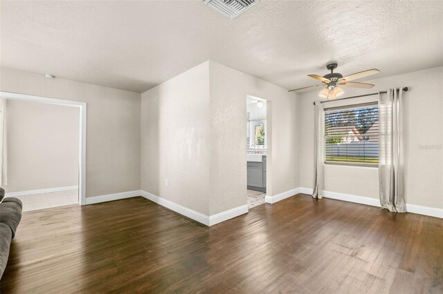 unfurnished living room featuring a textured ceiling, dark hardwood / wood-style floors, and ceiling fan