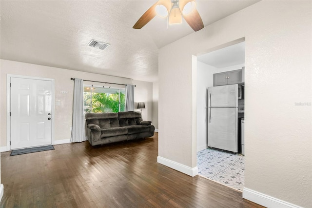 living room featuring ceiling fan, light hardwood / wood-style flooring, and a textured ceiling