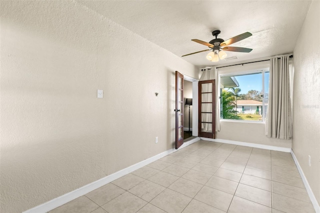 unfurnished room featuring a textured ceiling, ceiling fan, and light tile patterned flooring