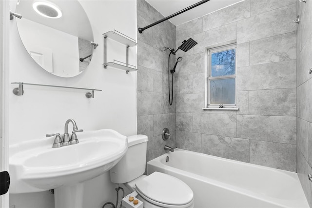 full bathroom featuring tiled shower / bath combo, toilet, and sink