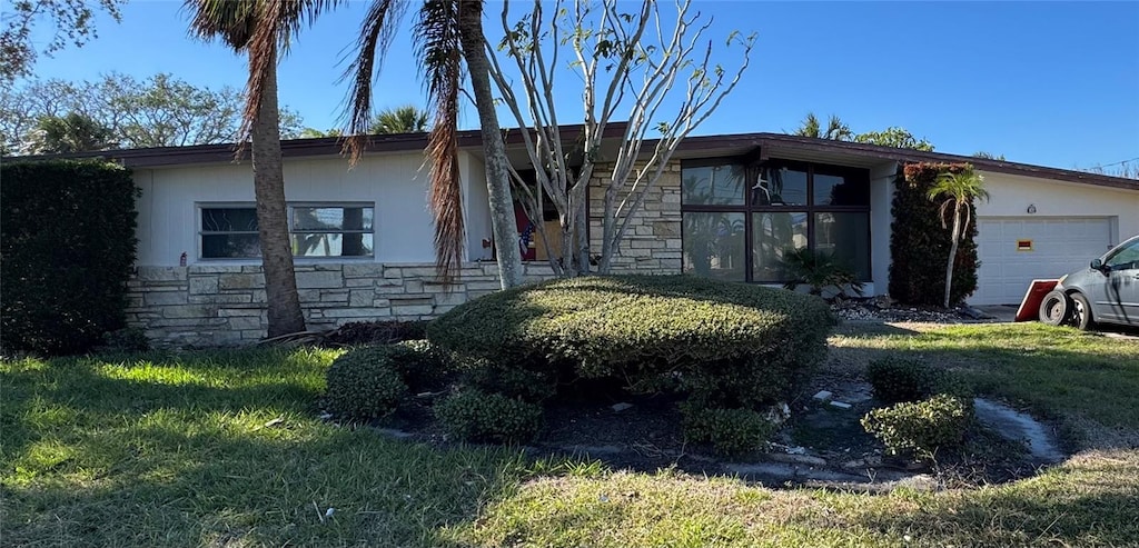 ranch-style home with a garage and a front lawn