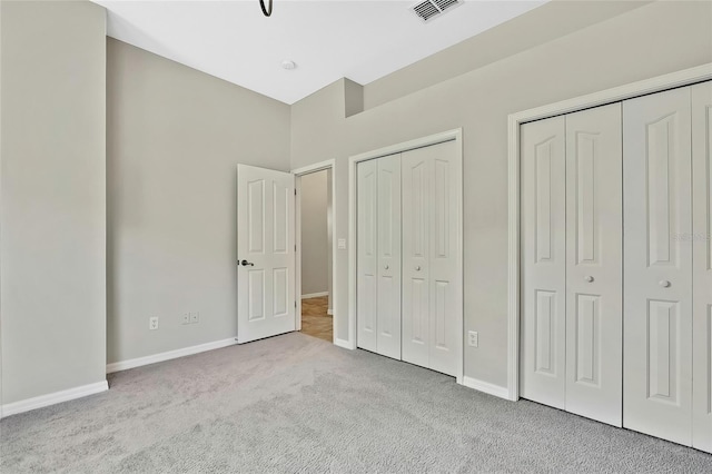 unfurnished bedroom with light carpet and multiple closets