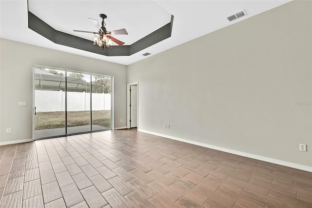 spare room with a raised ceiling, light hardwood / wood-style flooring, and ceiling fan