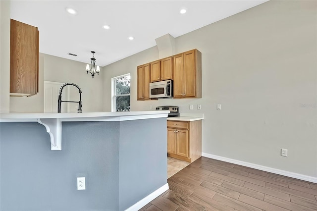 kitchen featuring sink, hanging light fixtures, light hardwood / wood-style flooring, kitchen peninsula, and a kitchen bar