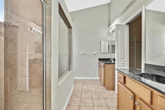 bathroom featuring tile patterned flooring, vanity, lofted ceiling, and walk in shower