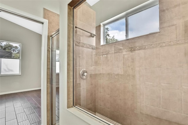 bathroom featuring lofted ceiling, a shower with door, and a wealth of natural light