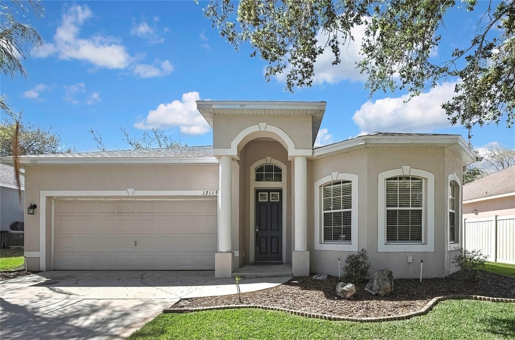 view of front facade featuring concrete driveway, an attached garage, fence, and stucco siding