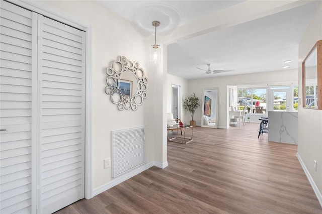 hall with visible vents, baseboards, and wood finished floors
