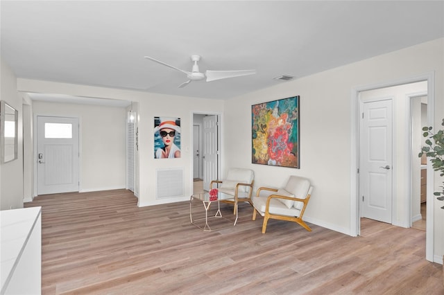 living area with light wood finished floors, baseboards, a ceiling fan, and visible vents