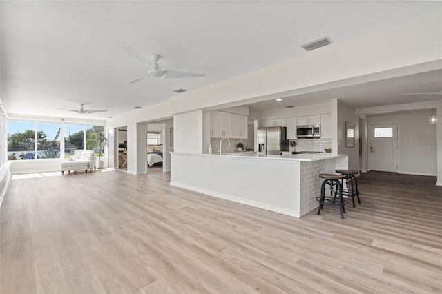 interior space with open floor plan, a ceiling fan, visible vents, stainless steel appliances, and a sink
