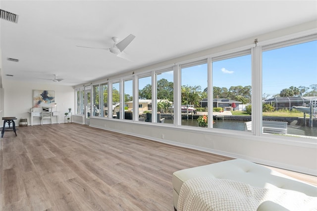 sunroom with a water view, a wealth of natural light, and visible vents